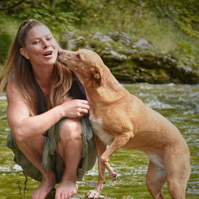 Bianca Oriana Willen, Gründerin der Hundeschule Willenskraft, lachend mit ihrer Hündin am Fluss